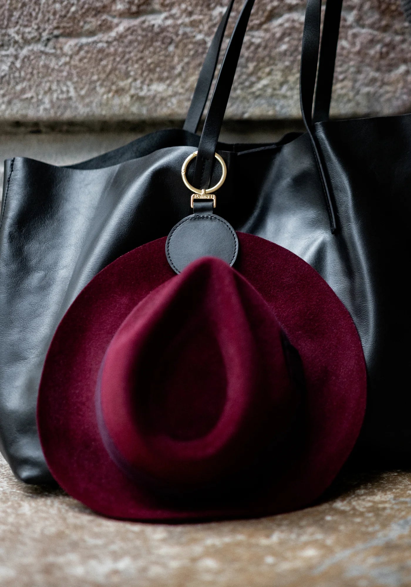 La pince à chapeau Sun noir de chez Palma B accrochée à un sac et à un chapeau