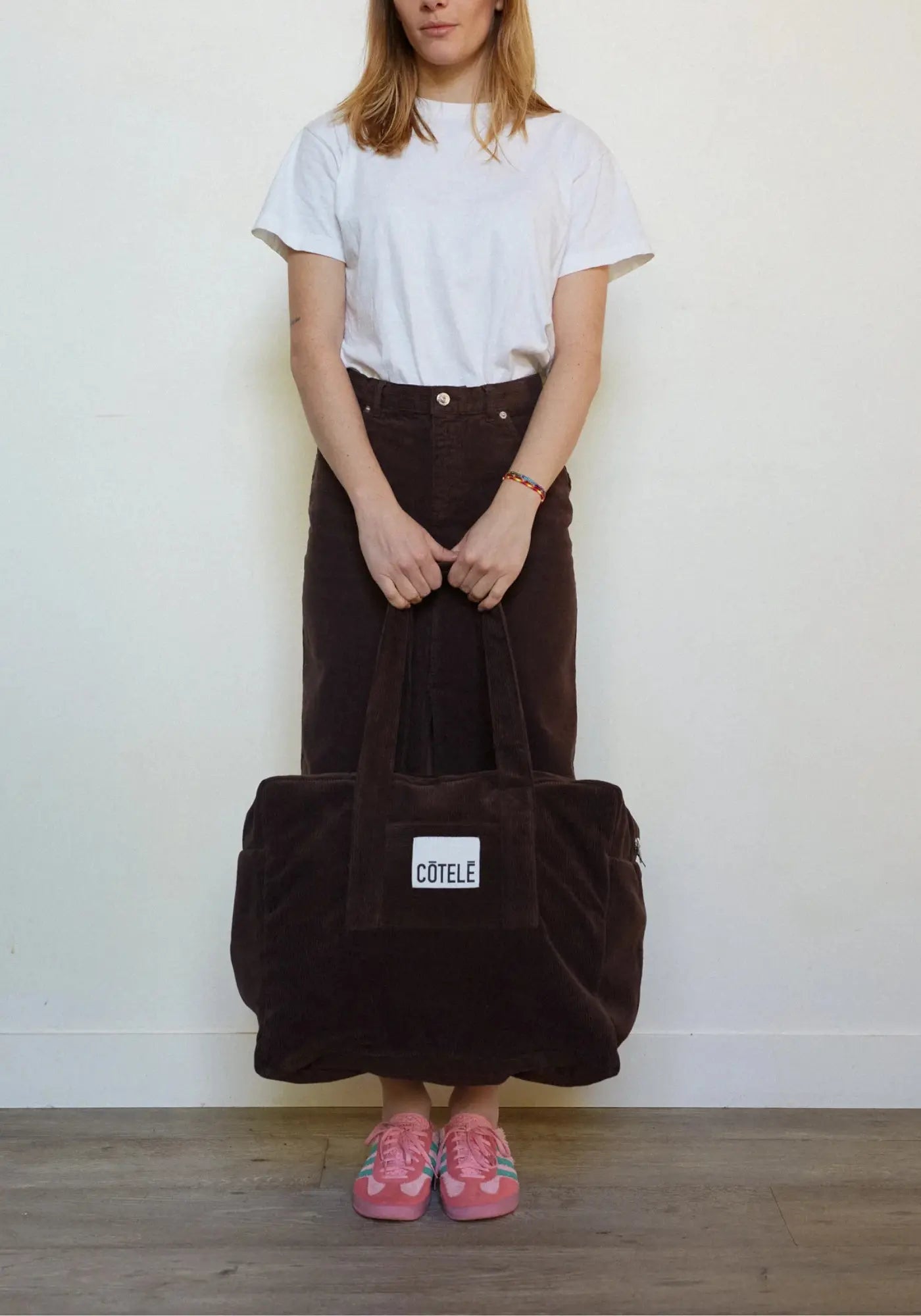 La femme porte le sac en velours week-end Bonny couleur chocolat de chez Côtelé Paris 