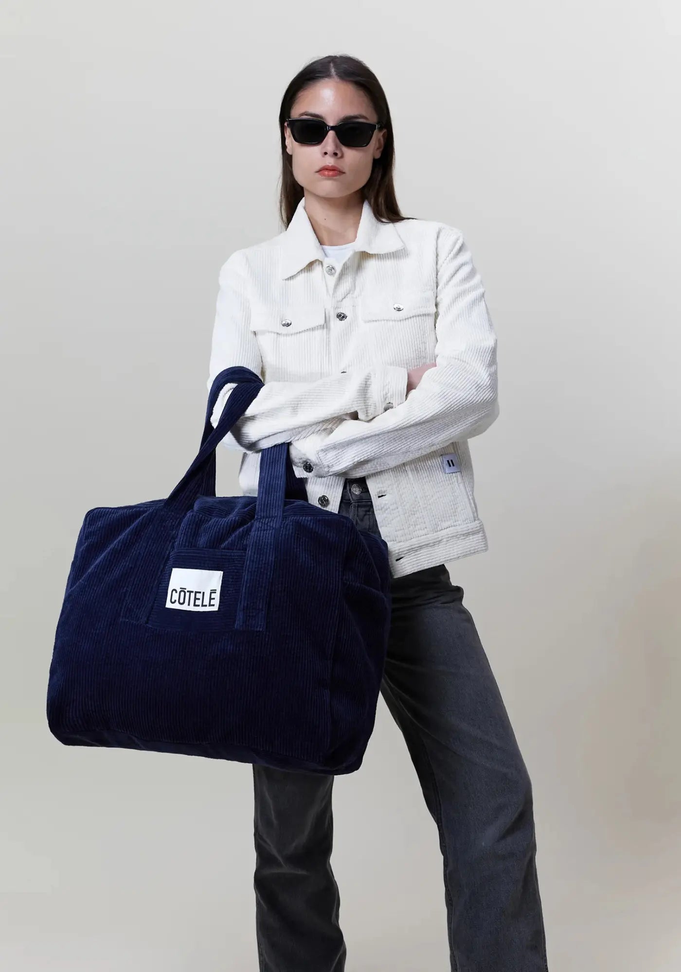 La femme porte le sac en velours week-end Bonny couleur navy de chez côtelé Paris 