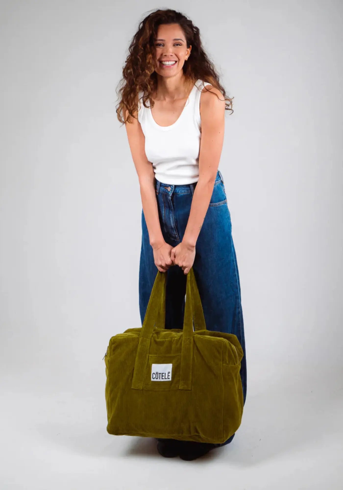 La femme porte le sac en velours week-end bonny pickle de chez Côtelé Paris 