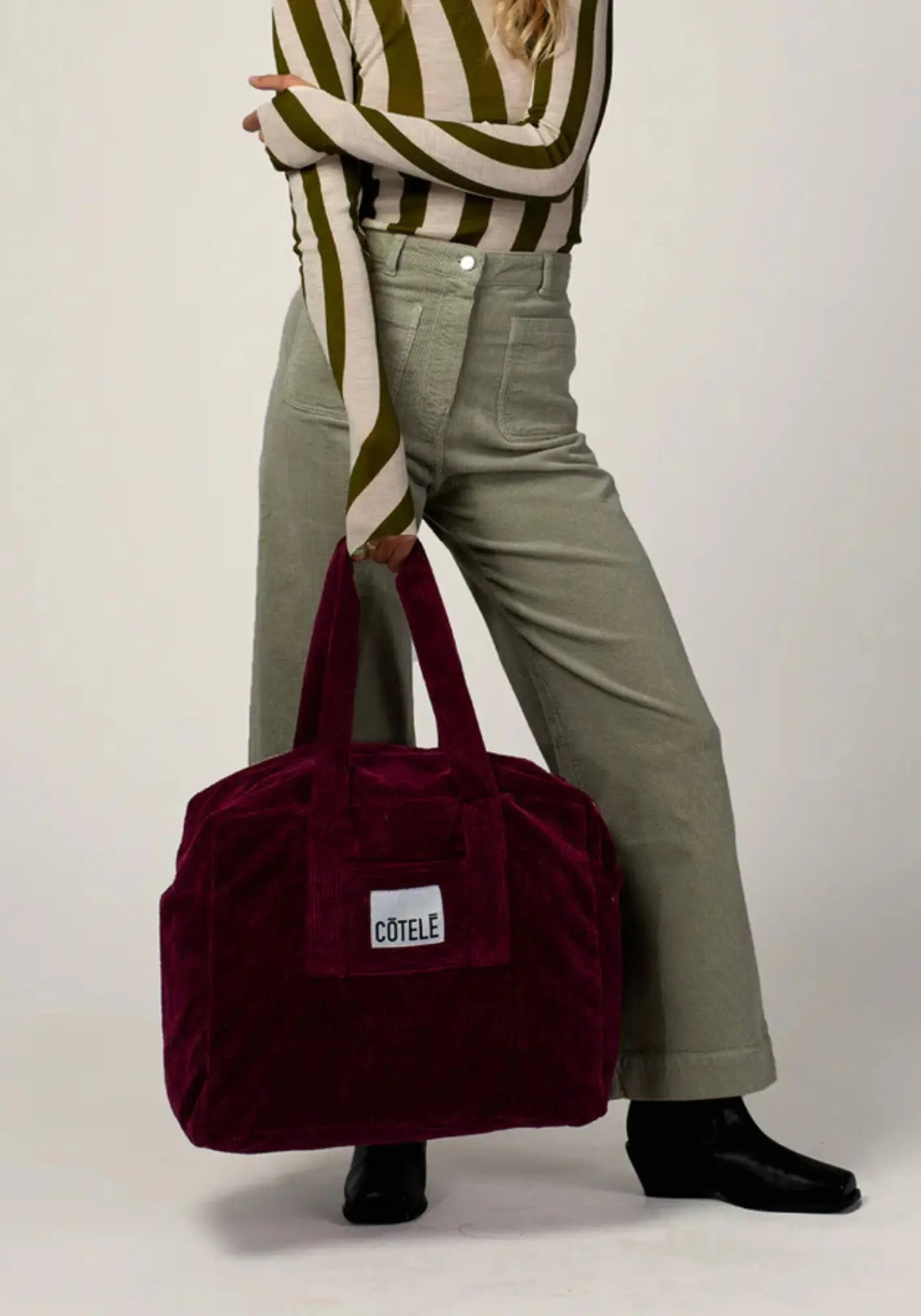 La femme porte le sac en velours week-end Bonny couleur prune de chez Côtelé Paris 