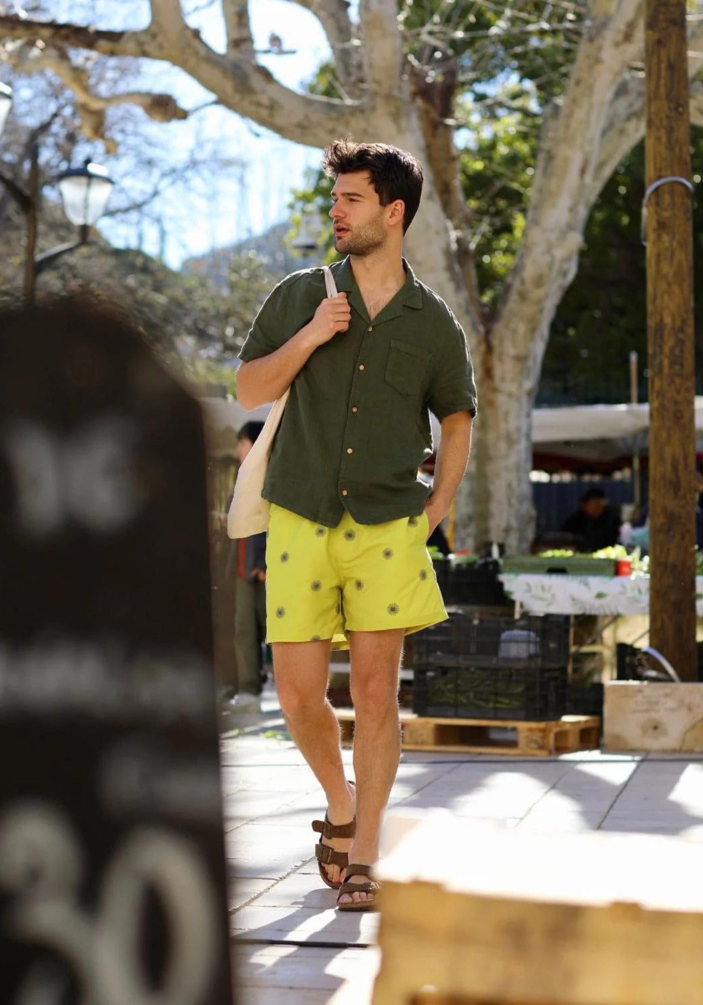 L'homme est au marché et porte le short de bain Les Verveines de chez Calanque