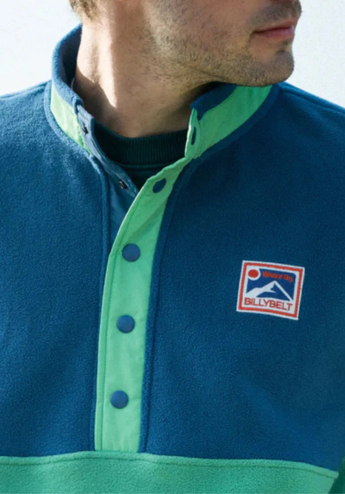 L'homme porte le sweat polaire marine et vert de chez Billybelt 
