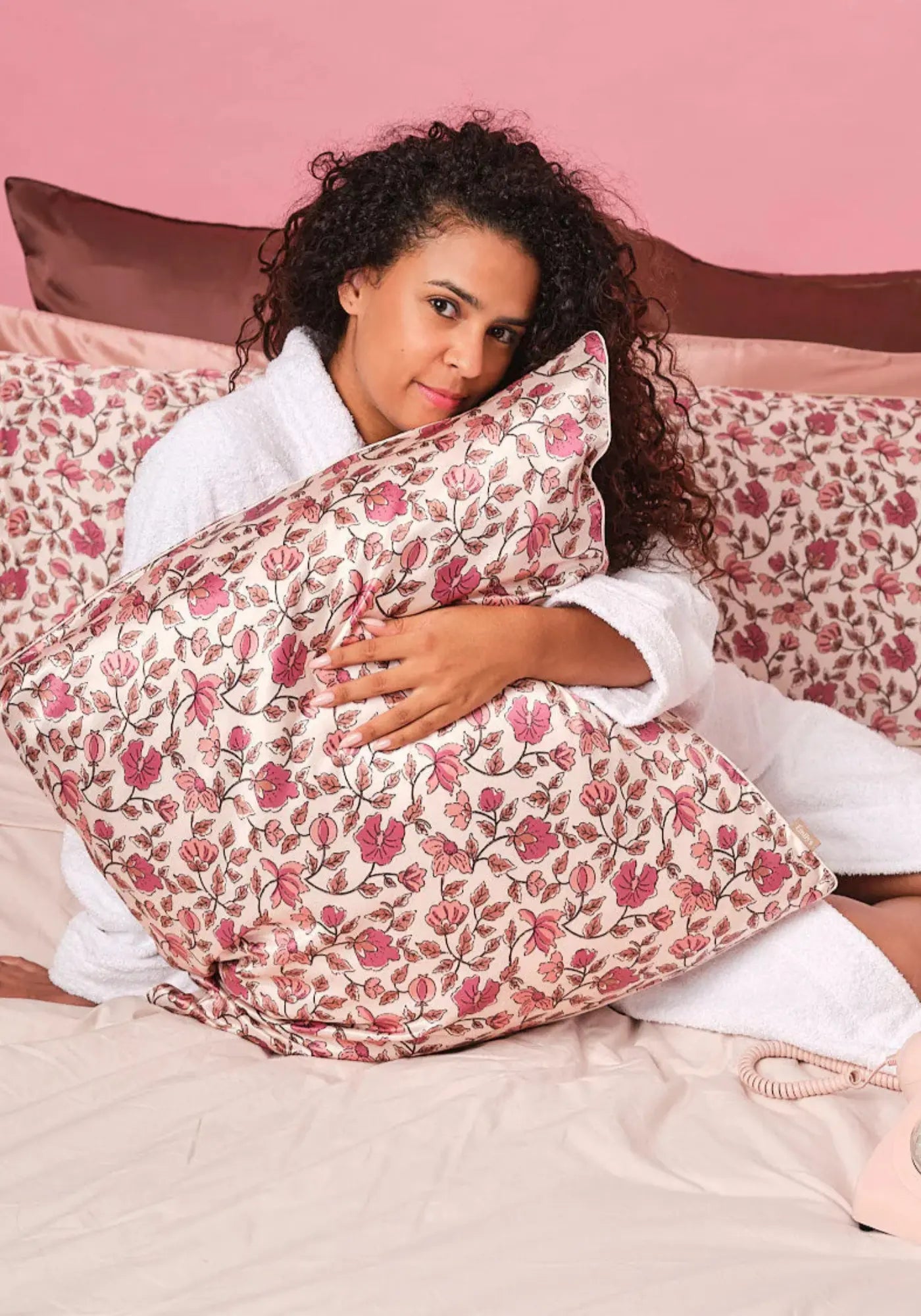 La femme tient dans ses bras la taie d'oreiller en soie carré fleurs d'automne de chez Emily's Pillow