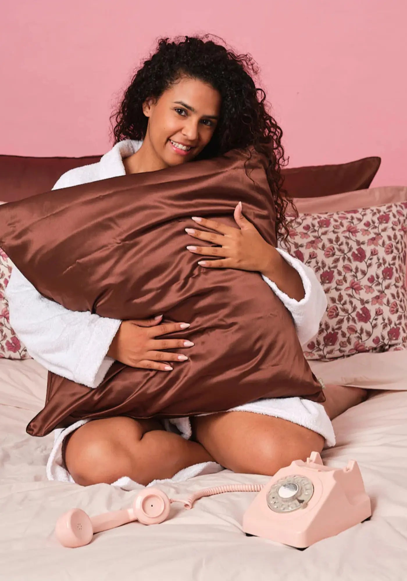La femme tient la taie d'oreiller en soie moka de chez Emily's Pillow