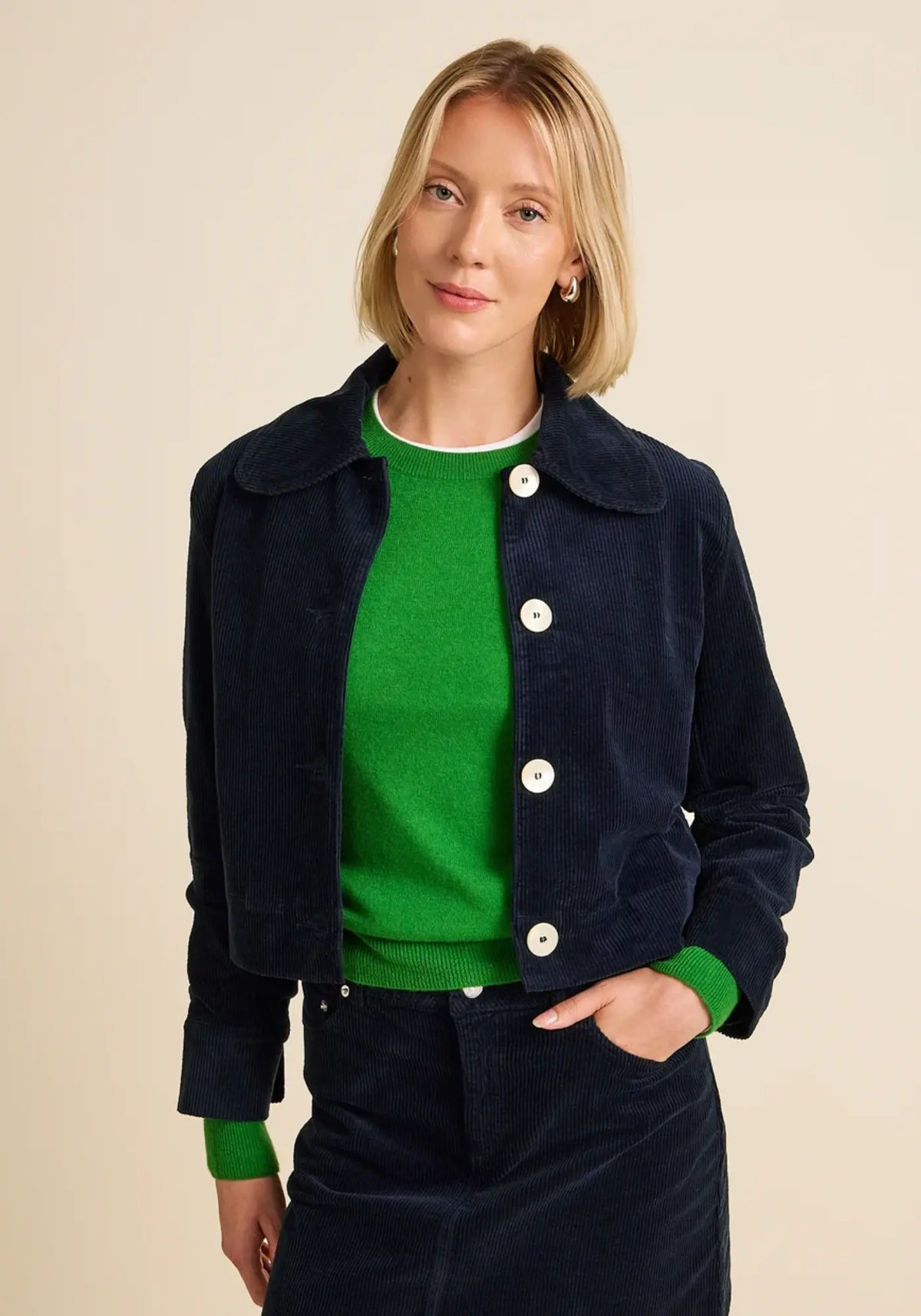 La femme porte la veste courte en velours daisy coloris navy de chez Côtelé Paris 