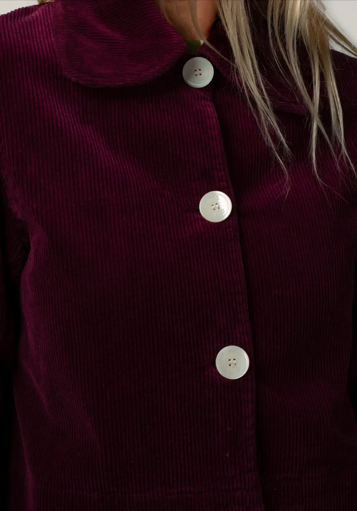 La femme porte la veste courte en velours daisy coloris prune de chez Côtelé Paris 