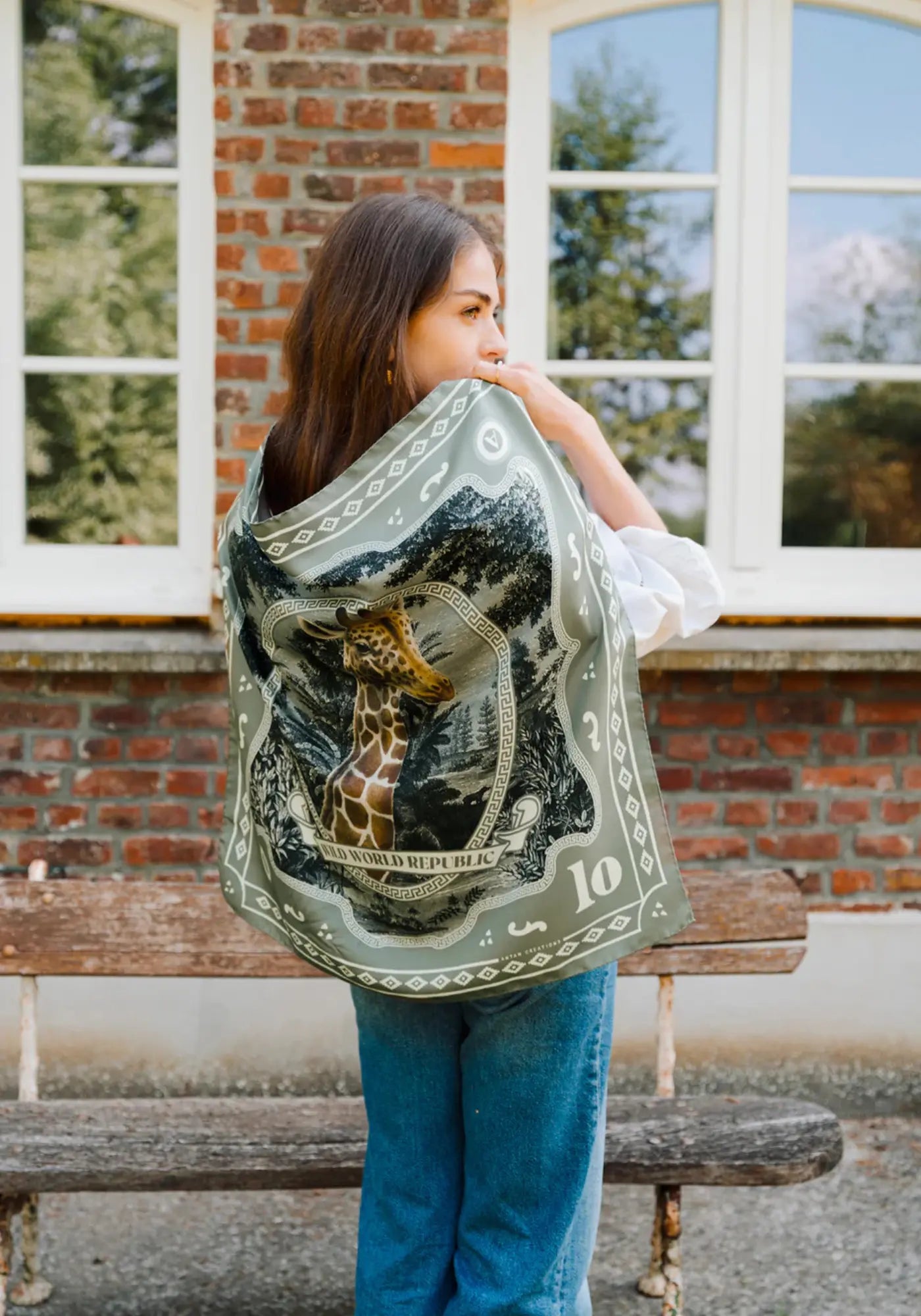 La femme porte le foulard wwr silk 70 giraffe de chez Antan Créations