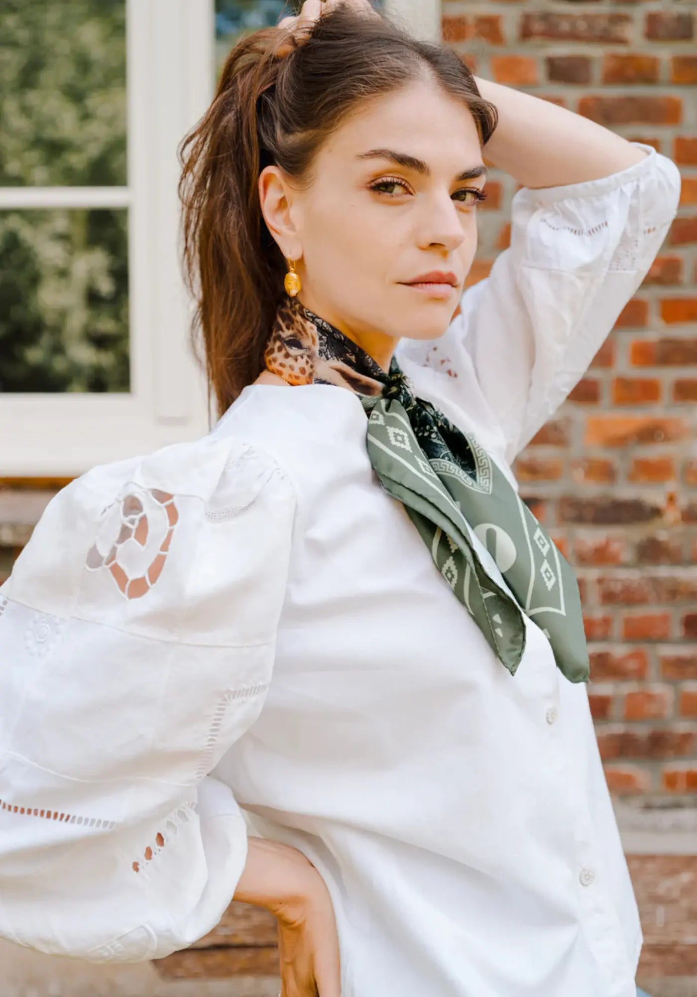 La femme porte le foulard wwr silk 70 giraffe de chez Antan Créations
